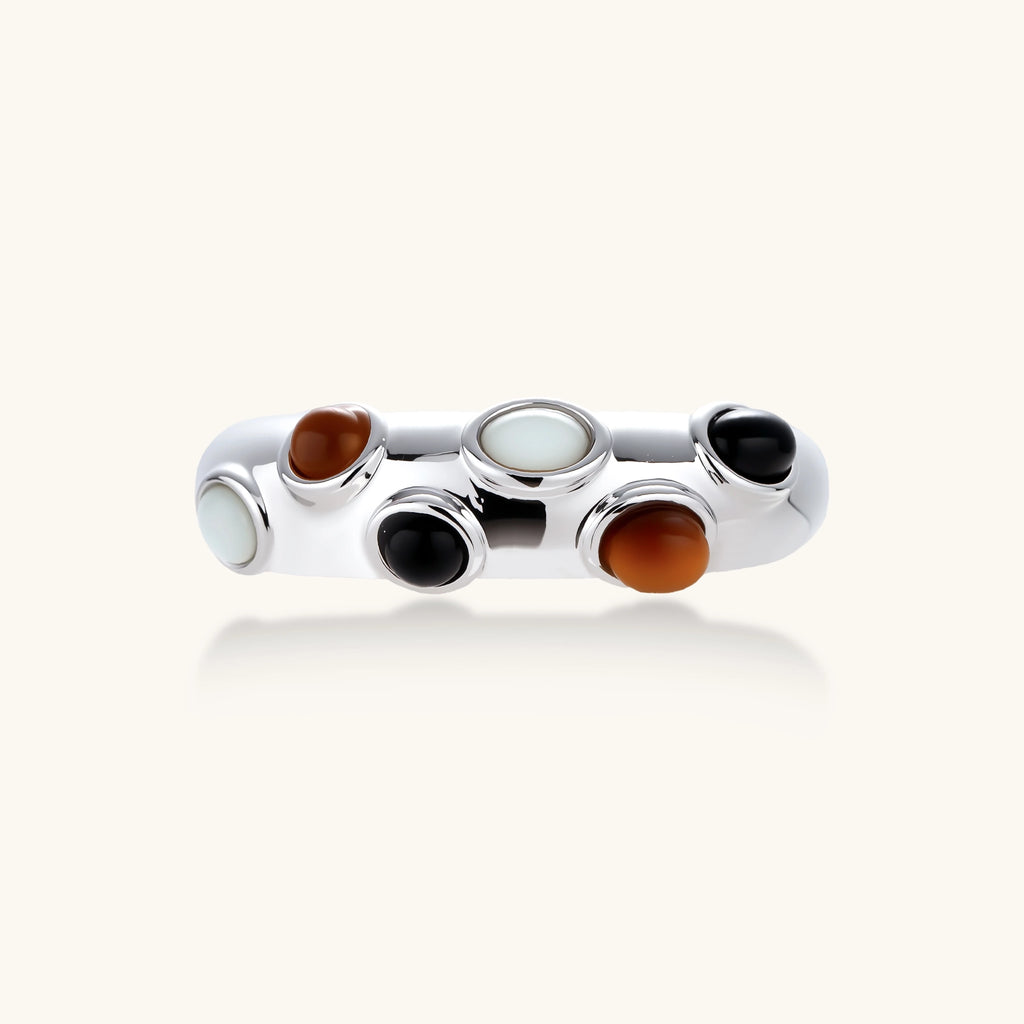 Chunky silver-tone adjustable open ring with black, brown and milky white oval cabochon stones on a cream background.