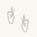 Silver star studs with crescent moon cutouts and zirconia stones connected by delicate chains on white background