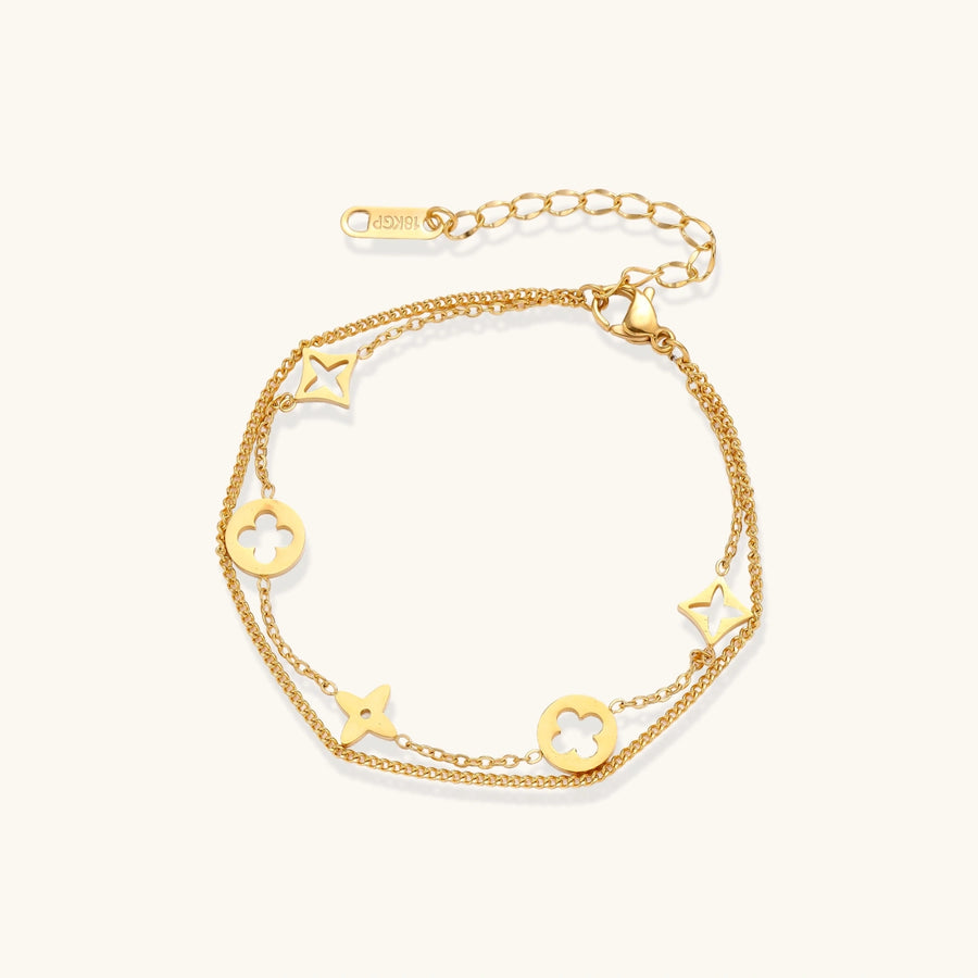 Double-layer gold-plated bracelet with quatrefoil and star charms on cream background, 18K gold finish.