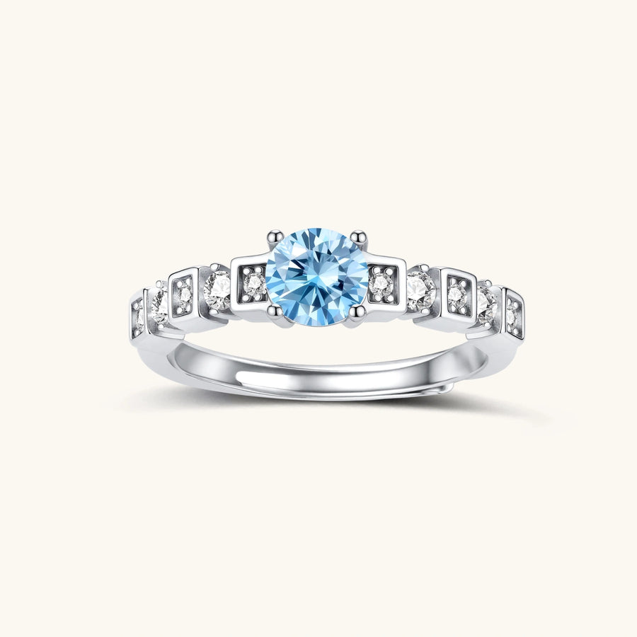 Geometric sterling silver ring with light blue moissanite center stone and square diamond accents on white background