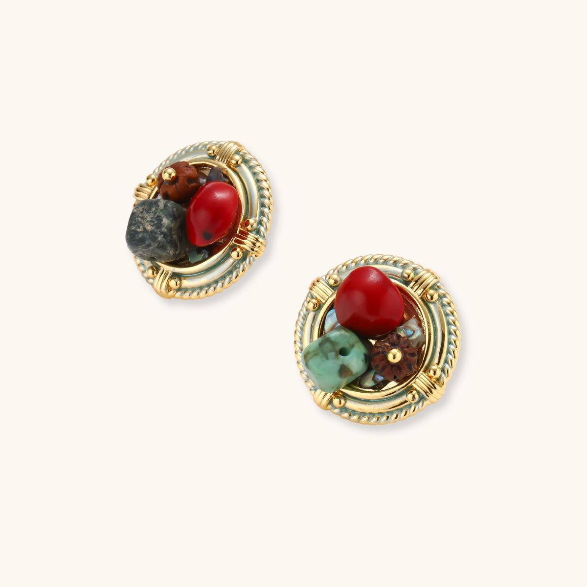 Pair of round gold-plated stud earrings with rope-twist borders, a red bead, brown wood bead and green turquoise on cream.