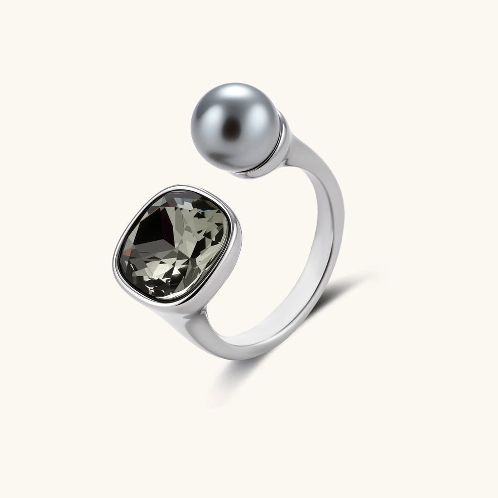 Open-cuff ring in white gold plated eco-brass with a smoky gray cushion-cut zirconia and a gray round bead on a cream background.